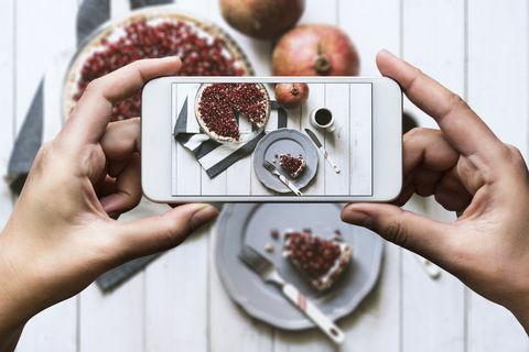 Mâna luând imaginea de sus fotografiat de masă Tarta de casă, completată cu rodie proaspătă și cană de cafea sunt pe masă