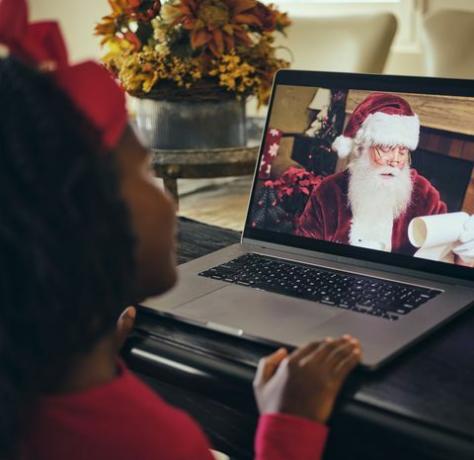 o fetiță, vorbind cu Moș Crăciun la o conferință video pe computer