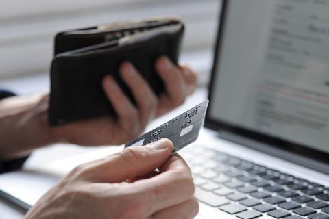 Mână care ține card de credit și portofel de laptop