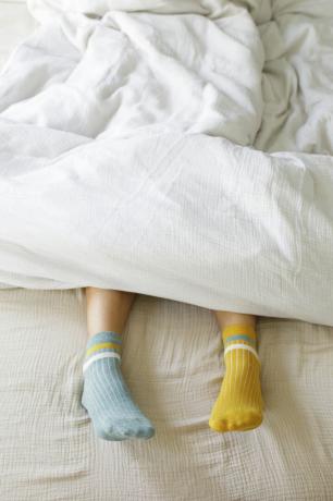 femeie care poartă șosete albastre și galbene în pat