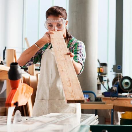 dulgher femeie verificând unghiul lemnului în atelier
